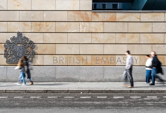 People walk past the British Embassy in Berlin, which has BRITISH EMBASSY carved into its stone wall