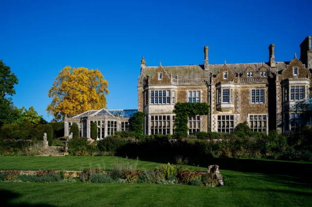 A view of Wiston House in the autmn sun with the gardens and trees turning yellow.